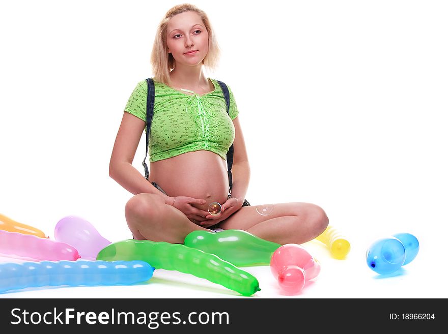 Cute pregnant girl, seated, surrounded by baloons