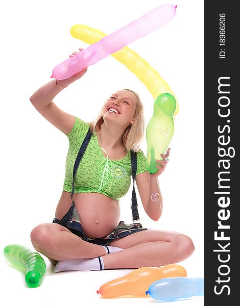 Cute pregnant girl, seated, surrounded by baloons