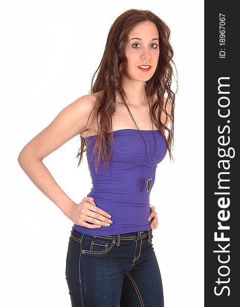 A pretty young woman in jeans, with a strapless top and long hair standing in the studio for white background. A pretty young woman in jeans, with a strapless top and long hair standing in the studio for white background.