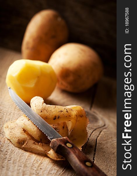 Potato, peel and knife on a rustic table. Potato, peel and knife on a rustic table