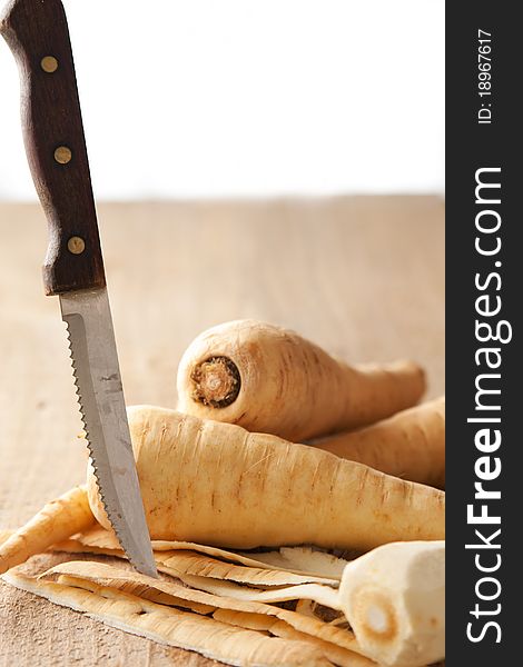 Parsley root, peel and knife on a rustic table