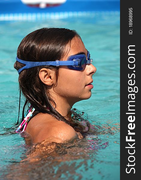Tanned girl in swimming pool wearing goggles. Tanned girl in swimming pool wearing goggles