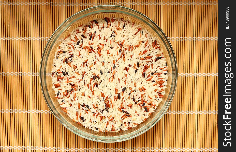 Raw rice in bowl on bamboo pad