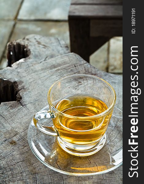 A glass cup of tea on wooden table in the garden. A glass cup of tea on wooden table in the garden