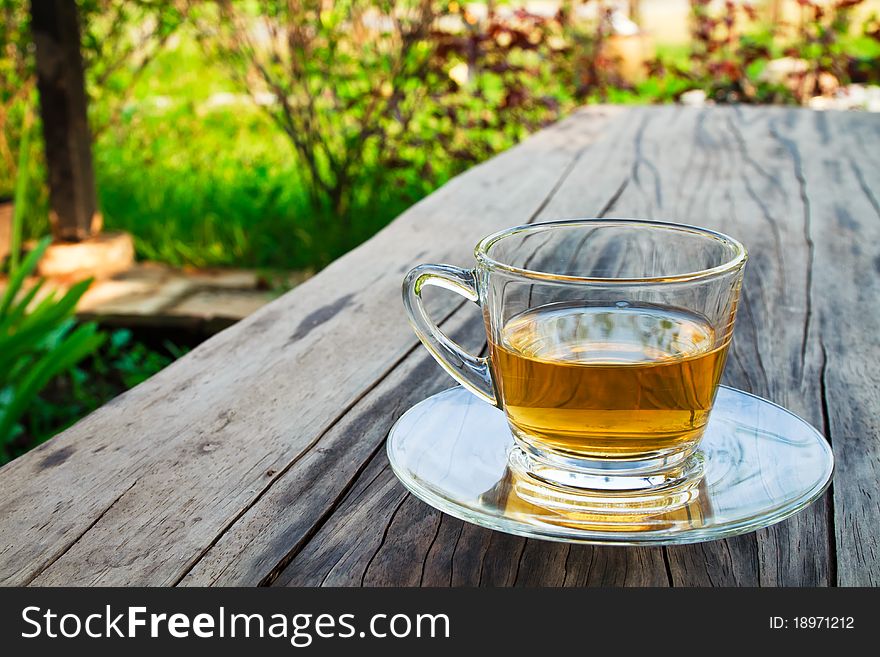 A glass cup of tea on wooden table in the garden. A glass cup of tea on wooden table in the garden