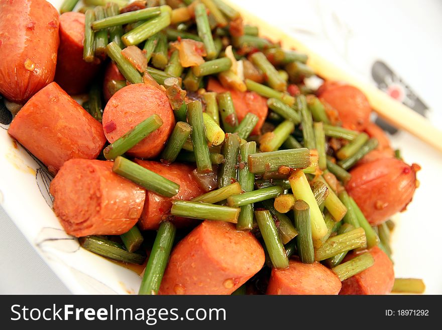 A fusion dish shot on white background: garlic sprouts and wieners. A fusion dish shot on white background: garlic sprouts and wieners.