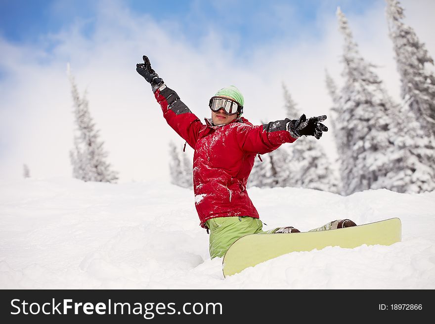 Snowboarder on the mountain with his arms raised