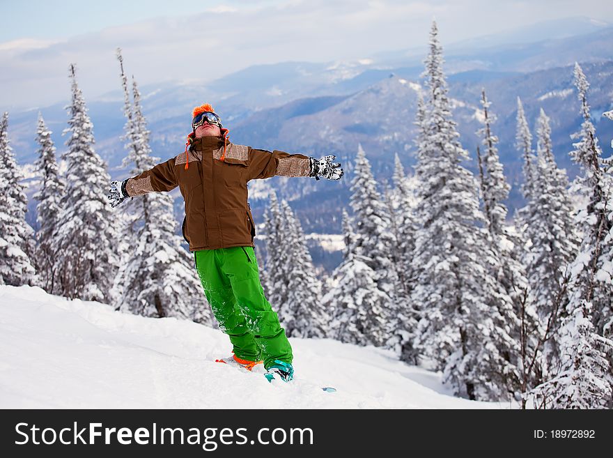 Snowboarder on the mountain with his arms raised