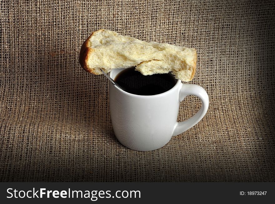 A coffee mug with a rusk on top of it. Photographed in a studio. A coffee mug with a rusk on top of it. Photographed in a studio.