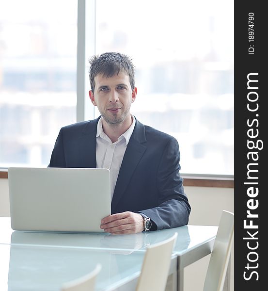 Young business man lawyer with laptop alone in big bright   conference room. Young business man lawyer with laptop alone in big bright   conference room