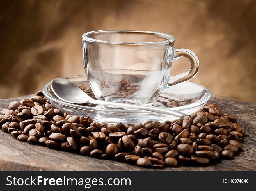Photo of empty glass cup on coffee beans over wooden table