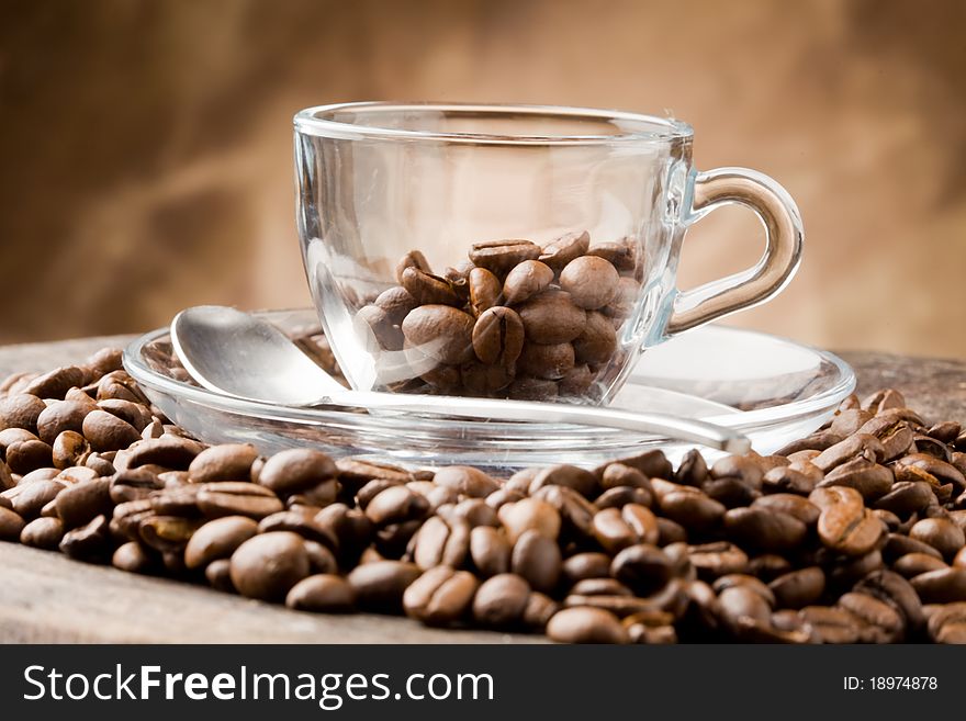 Photo of empty glass cup on coffee beans over wooden table