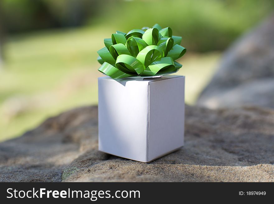 A little white gift box sits on a rock like a gift from Mother Nature. A little white gift box sits on a rock like a gift from Mother Nature.