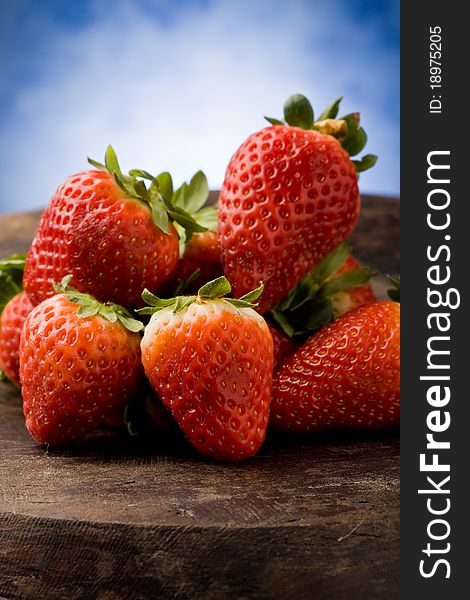 Photo of delicious red strawberries on wooden table in front of a blue background