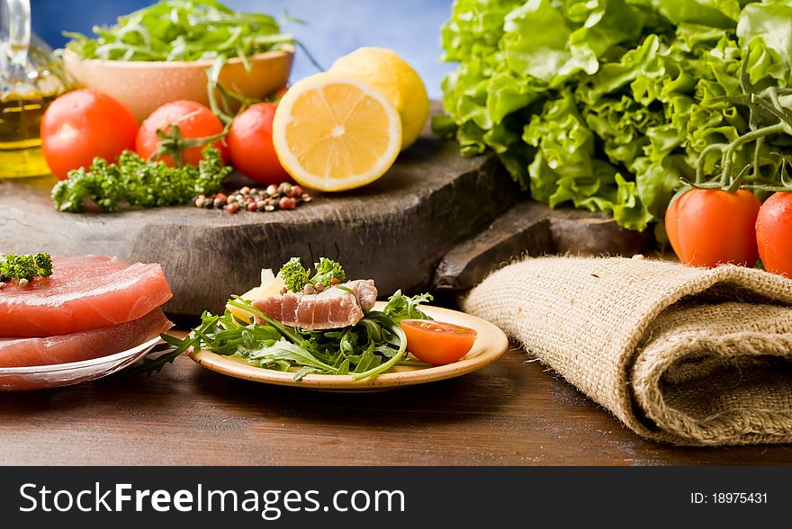 Photo of sliced Tuna Steak with arugula salad and ingredients arround