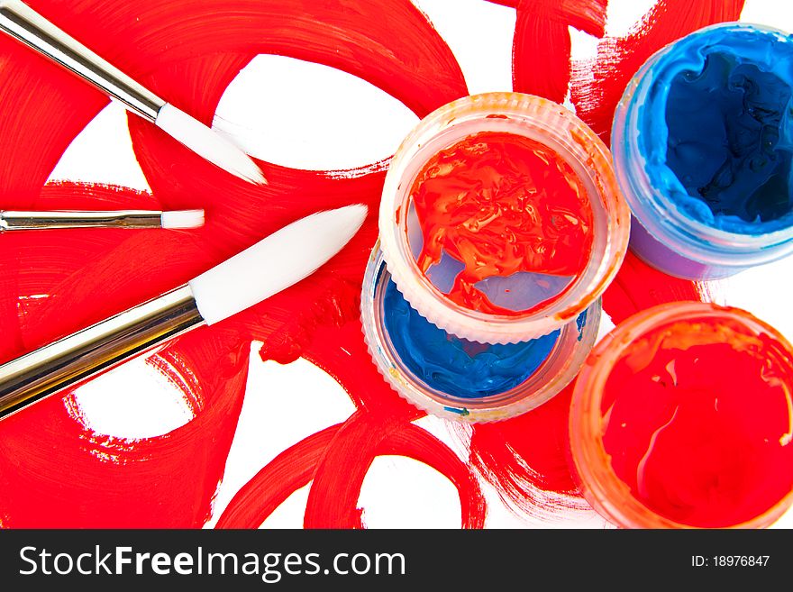 Three brushes and tubes with paint on white