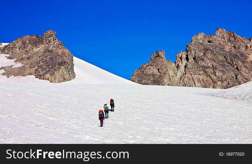 Climbers in the snowy mountains with rocks and deep blue sky