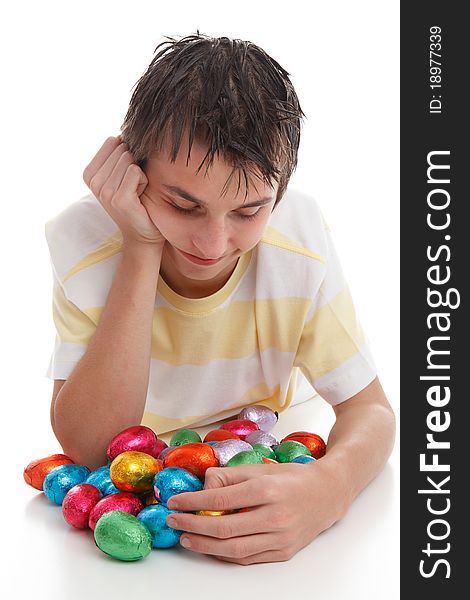 A boy looking down at lots of colourful bright chocolate easter eggs. A boy looking down at lots of colourful bright chocolate easter eggs.