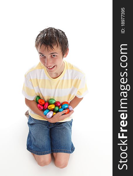 Boy holding an armful of colorful chocolate easter eggs and smiling. White background,. Boy holding an armful of colorful chocolate easter eggs and smiling. White background,