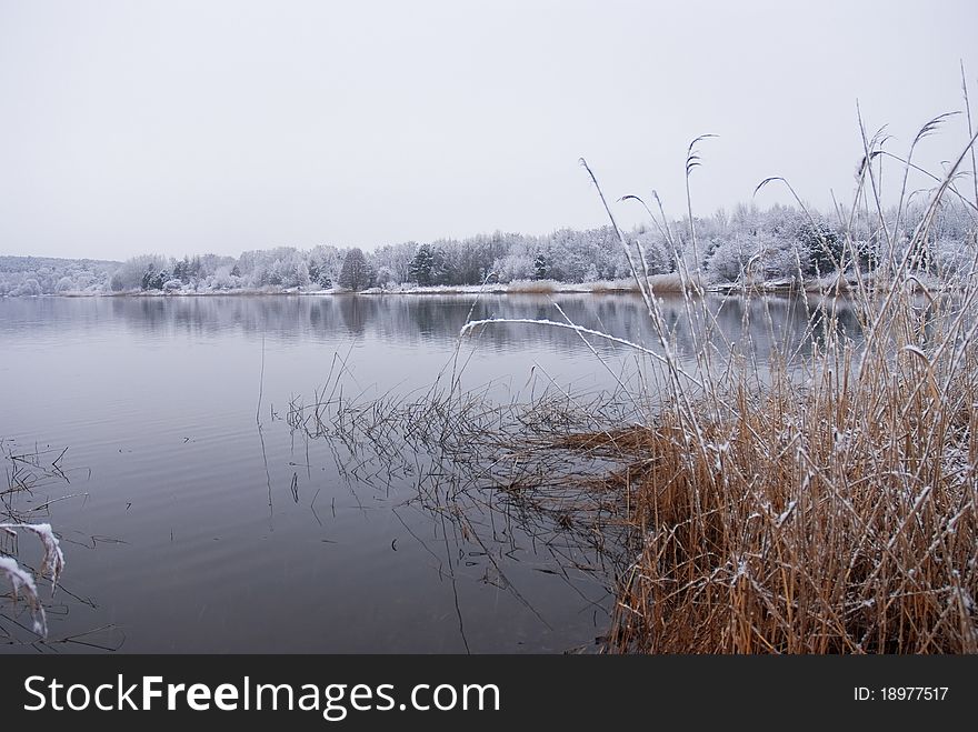 Frozen thawing lake in snow landscape.