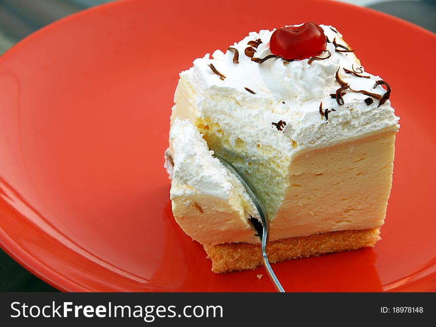 Sweet appetizing creamy cookie on red plate with spoon. Sweet appetizing creamy cookie on red plate with spoon