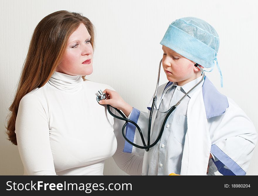 The boy plays the doctor. Listens a stethoscope to the mum