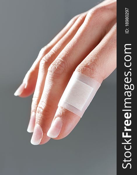 Bandage on female finger, isolated on gray