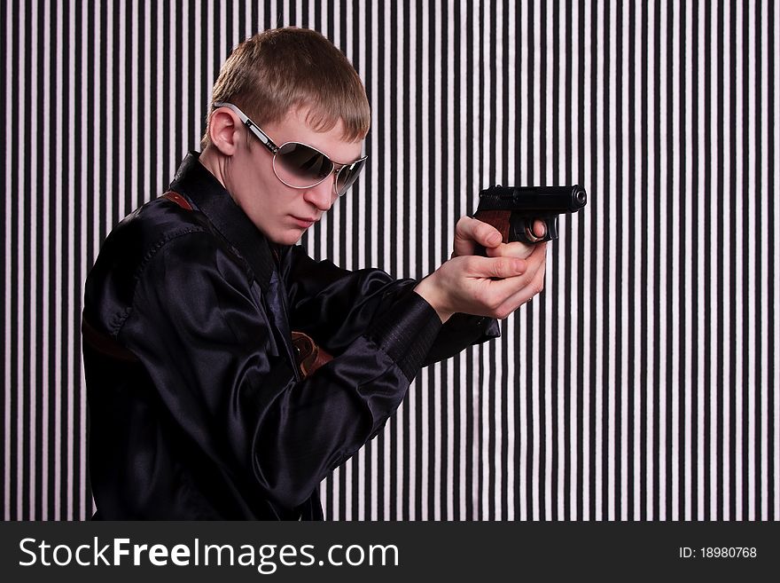 Serious man with a gun standing against striped background