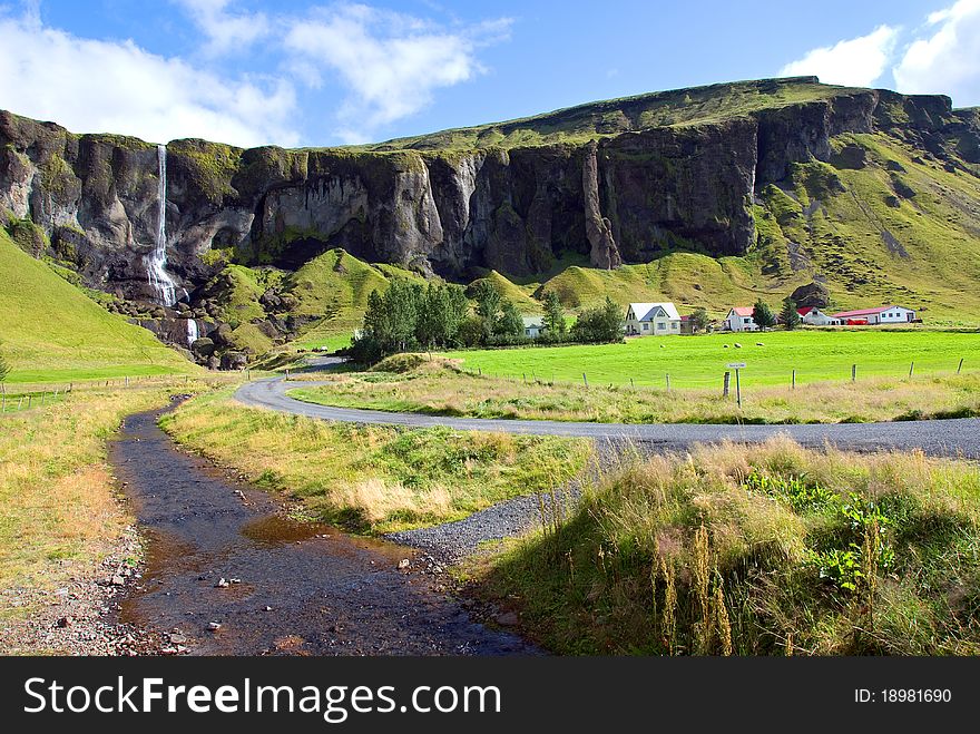 Iceland street flanked by mountains with a waterfall. Iceland street flanked by mountains with a waterfall