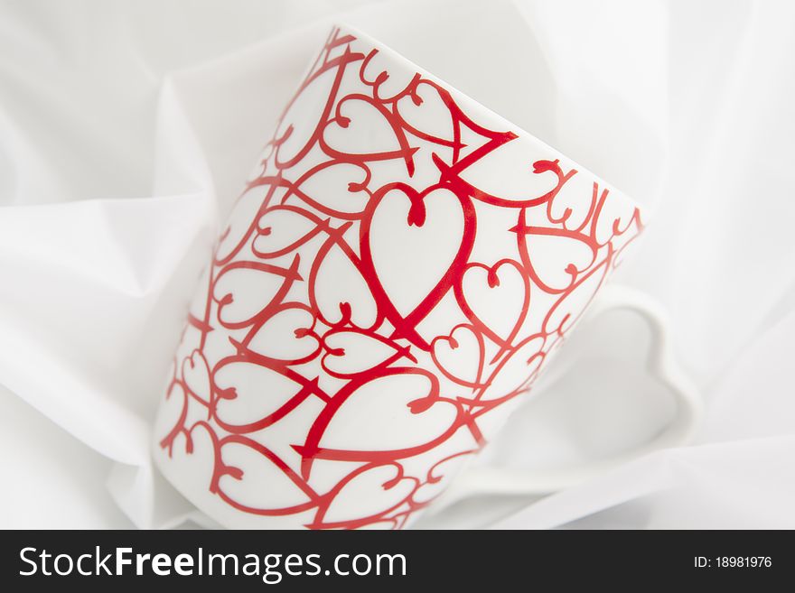 Close up , on a white background, of a cup with stylized hearts printed on it. Close up , on a white background, of a cup with stylized hearts printed on it