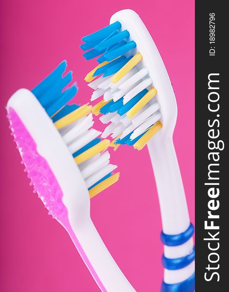 A couple of toothbrushes over pink background