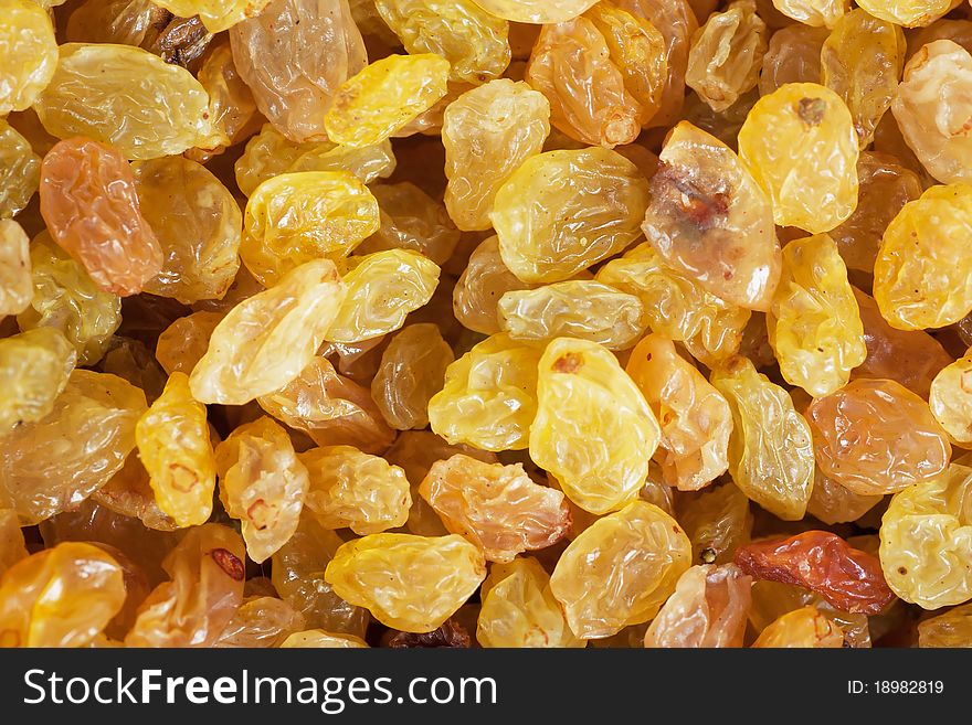 Background of golden, yellow and brown shiny raisins made from white grapes. Background of golden, yellow and brown shiny raisins made from white grapes