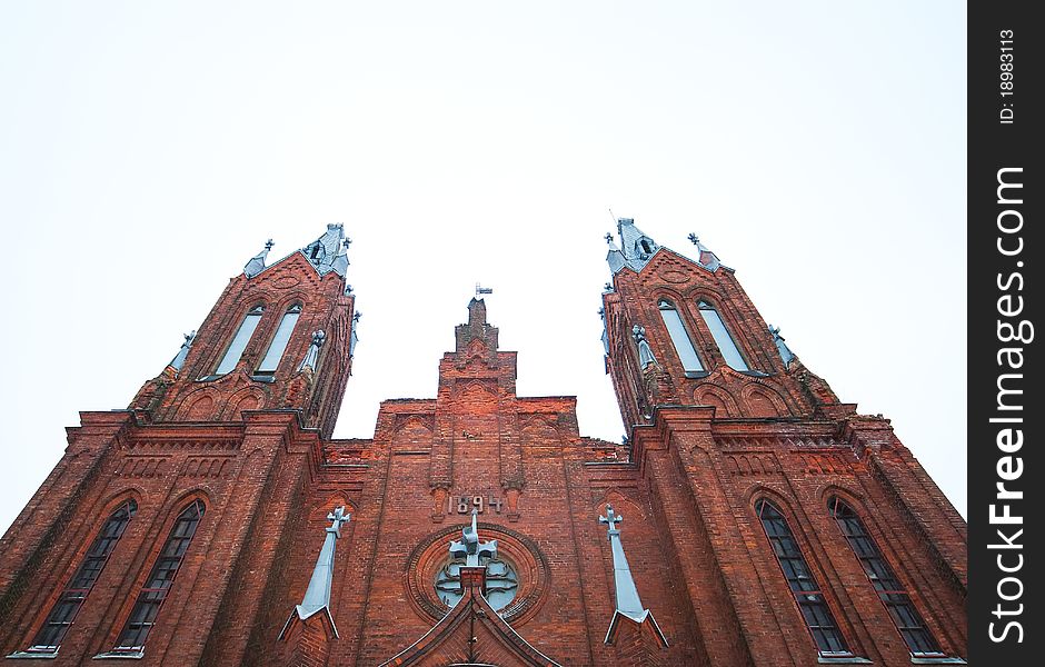 Ancient Catholic cathedral of red brick on sky background