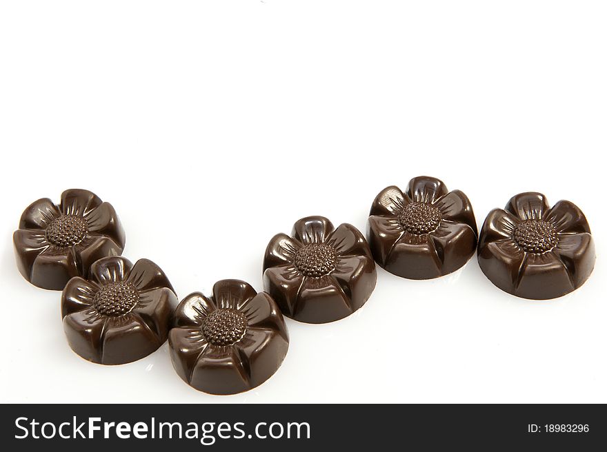 Some chocolates in the shape of flower on white background