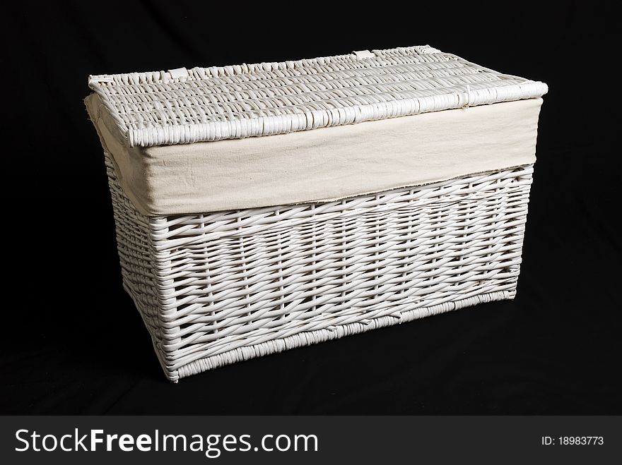 A closed white wicker toy basket isolated against a black background. A closed white wicker toy basket isolated against a black background