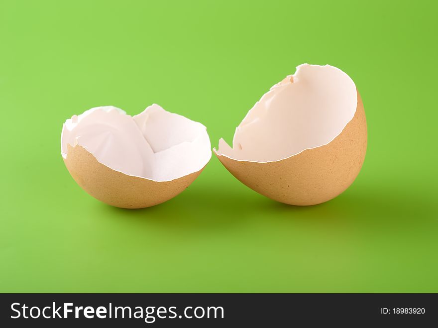 Two pieces of brown egg shell on a green background