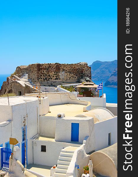 Beautiful empty street and traditional architecture on island of Santorini in Oia, Greece. Ruins and Aegean sea in a background. Beautiful empty street and traditional architecture on island of Santorini in Oia, Greece. Ruins and Aegean sea in a background.