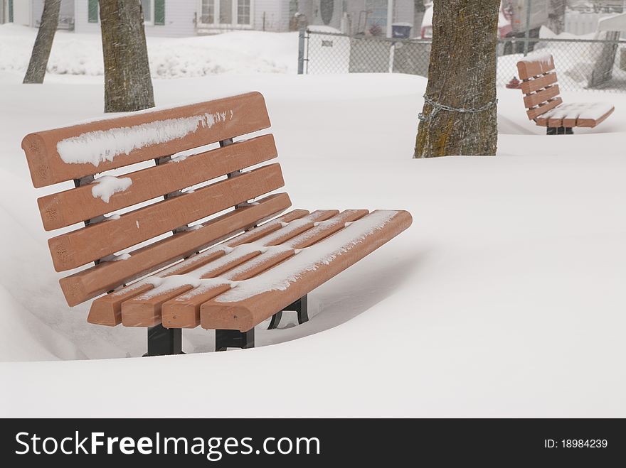 This is two orange bench in a park in a snow storm. This is two orange bench in a park in a snow storm.