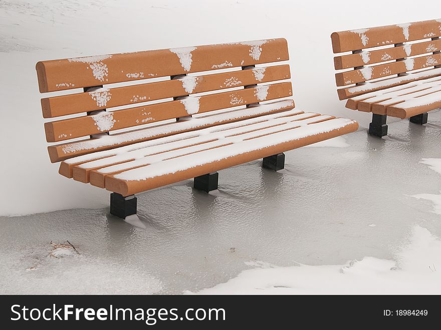 This is two orange bench in a park in a snow storm. This is two orange bench in a park in a snow storm.