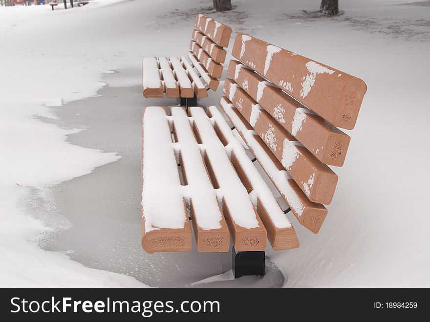 This is two orange bench in a park in a snow storm. This is two orange bench in a park in a snow storm.