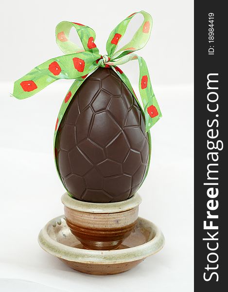 Dark chocolate Easter egg with a bow in a cup
