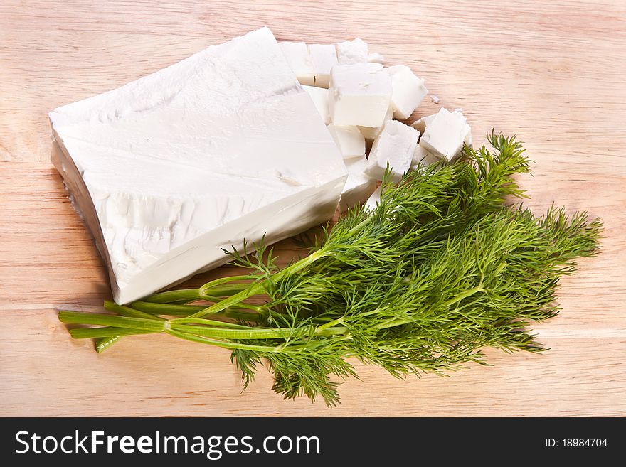 Slab of feta cheese and fresh dill on the cutting board