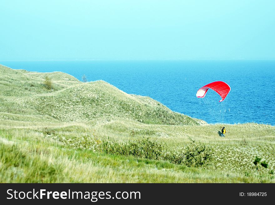 Red paragliding near blue sea