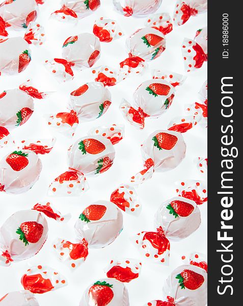 Strawberry candies in plastic wraps on white background