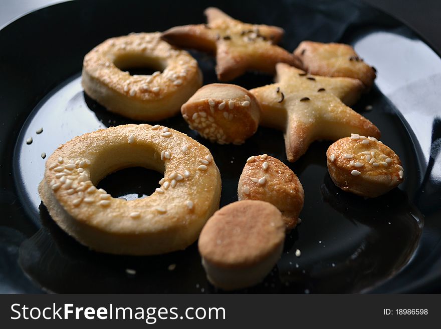 Multiple hard pretzels with sesame and caraway on black plate. Multiple hard pretzels with sesame and caraway on black plate