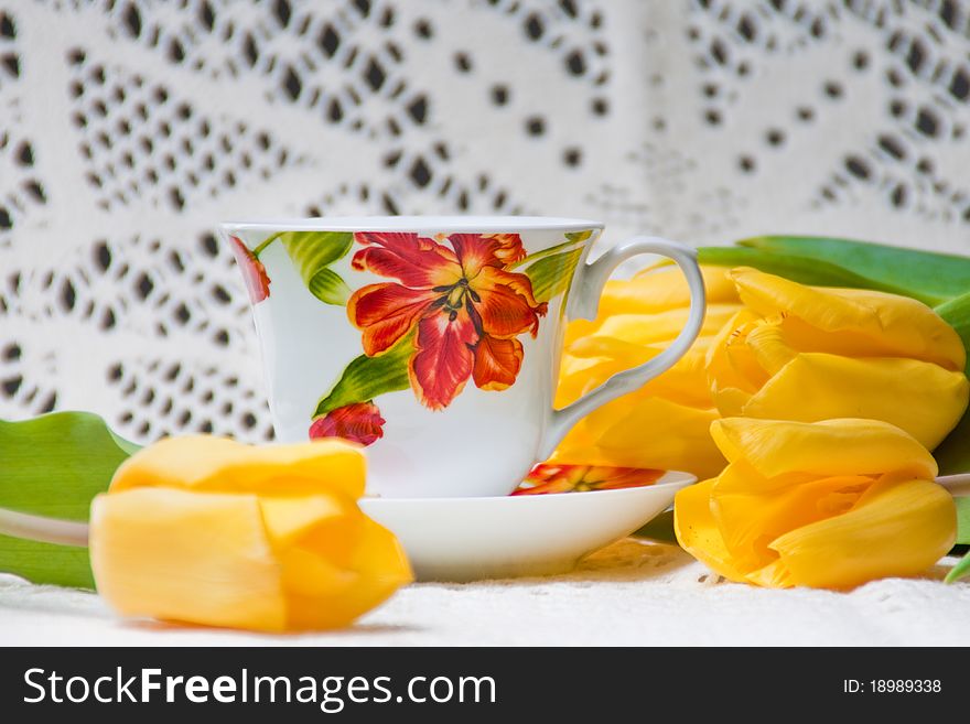 White cup of tea with red and yelow flowers. White cup of tea with red and yelow flowers