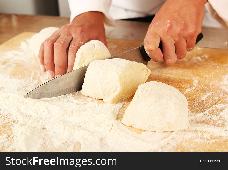 Chef cutting dough into segments on a chopping board