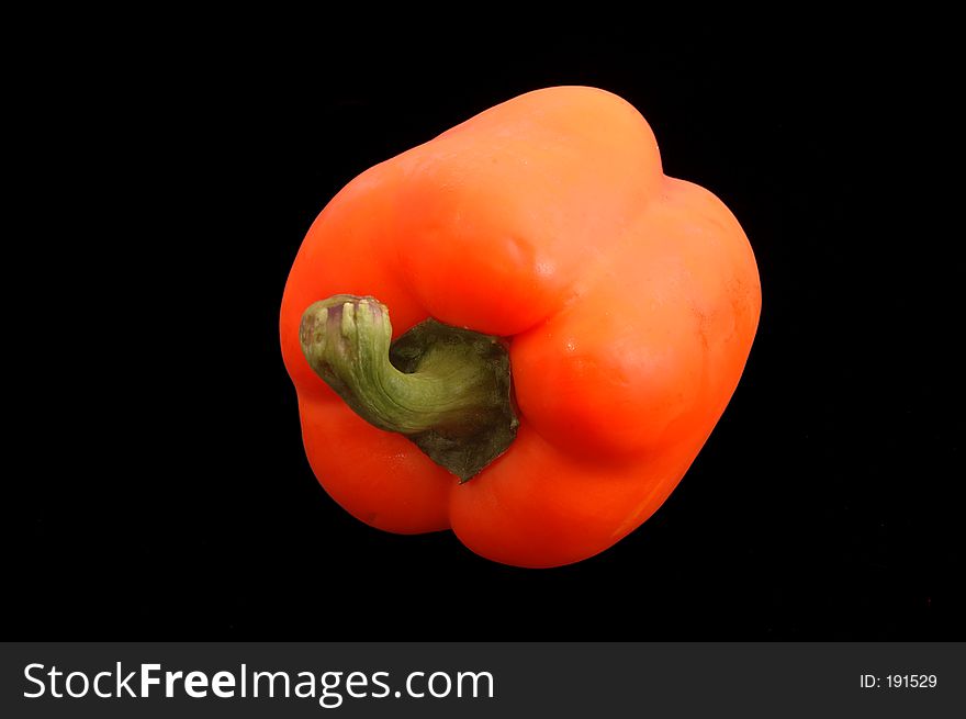 A fresh orange bell pepper over black