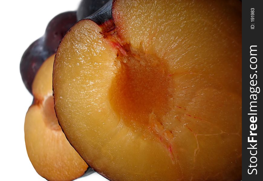 Split black plums in close detail. Split black plums in close detail.