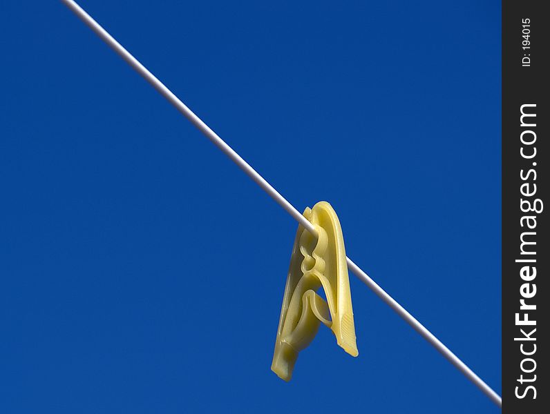 Yellow peg on clothes line against a blue sky